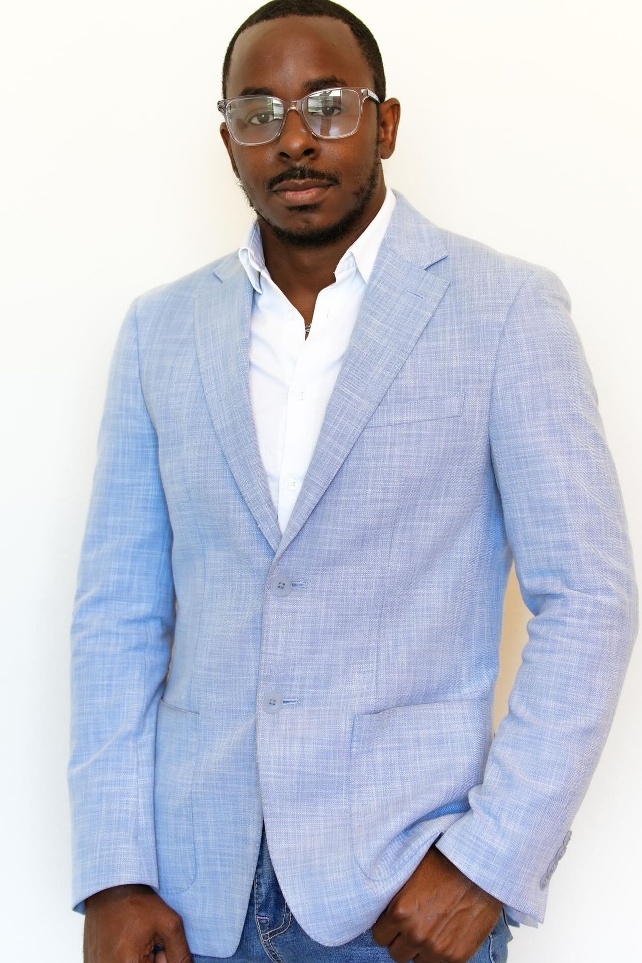 Marzuwq Muhammad wearing a pale blue blazer and clear glasses